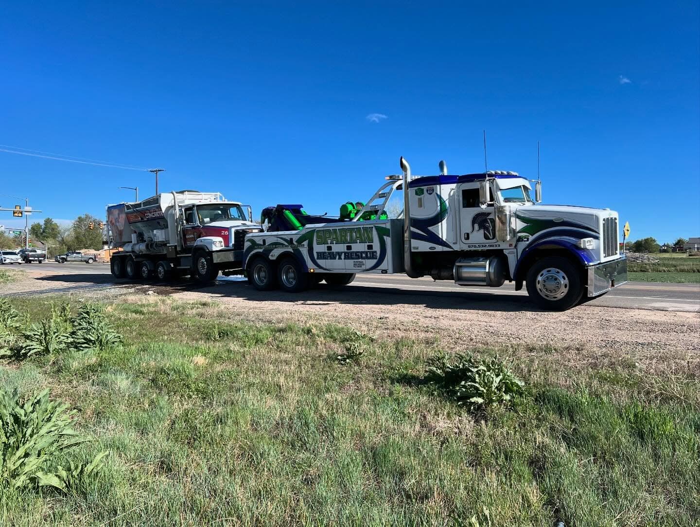Three white Spartan trucks parked in a row under a clear sky