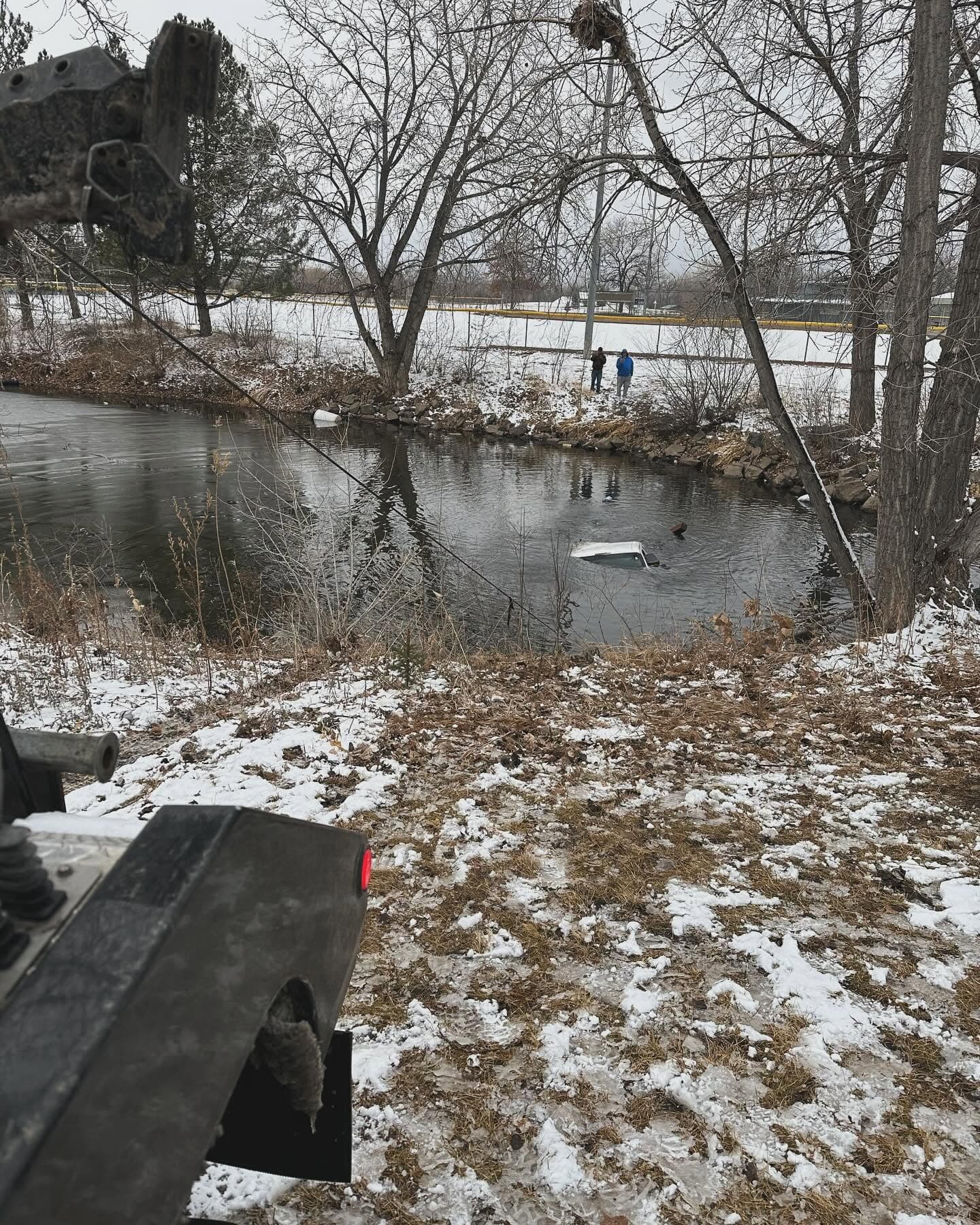 Tow truck winching a stuck vehicle out of river water