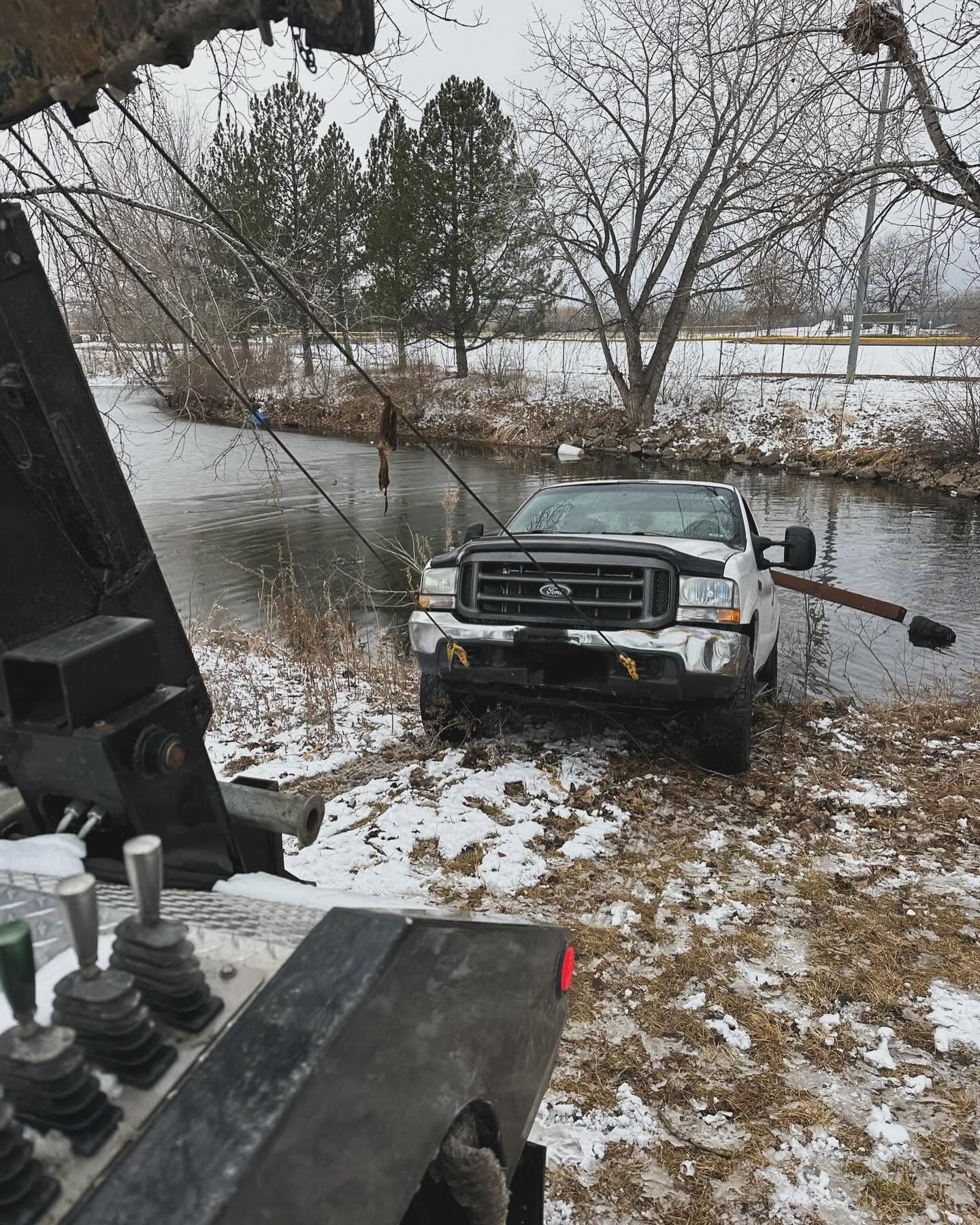 Tow rig with cable winch extracting a stranded truck from a river