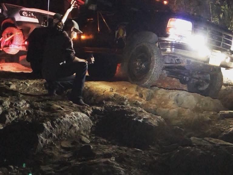 Nighttime recovery on rocky terrain with crew working in headlights